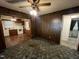 Living room view features paneled walls, ceiling fan with lights, and doorway to the kitchen and bathroom at 2612 Academy St, Sanford, NC 27332