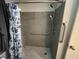 Updated walk-in shower featuring gray tile surround, grab bar, and blue floral shower curtain at 2612 Academy St, Sanford, NC 27332