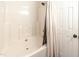 Classic tub and shower combination with neutral tones and an elegant shower curtain and a white bathroom door at 30 Cheltenham Dr, Clayton, NC 27520