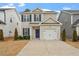 Two-story tan house with a white garage door and blue front door at 36 Schoolhouse Way, Clayton, NC 27520