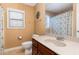 Tan bathroom with a toilet, tan sink, and matching cabinets with a framed mirror at 3905 Song Sparrow Dr, Wake Forest, NC 27587