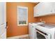Orange laundry room with a washer and dryer and white cabinets above at 3905 Song Sparrow Dr, Wake Forest, NC 27587