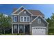 Two-story house with gray siding, white garage door, and a front porch at 3205 Armeria Dr, Apex, NC 27502