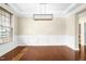 Bright, empty dining room with hardwood floors, wainscoting, and a modern light fixture at 10511 Sablewood Dr # 110, Raleigh, NC 27617