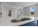 Close-up of a kitchen island with a stainless steel sink, white countertops, and modern fixtures at 107 Barn Door Dr, Lillington, NC 27546