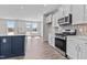 Modern kitchen with stainless steel appliances, sleek white cabinets, and a large blue kitchen island at 107 Barn Door Dr, Lillington, NC 27546