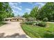 Beautiful home with a circular driveway and a lush, landscaped front yard with various plants and flowers at 12044 Iredell, Chapel Hill, NC 27517