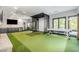 Spacious recreation room with an indoor golf simulator, kitchenette, and large windows offering natural light at 12044 Iredell, Chapel Hill, NC 27517