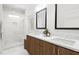 Modern bathroom featuring double sinks, wood cabinets, stylish mirrors, and a glass-enclosed shower at 3021 White Rail Dr, Fuquay Varina, NC 27526
