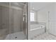 Bright bathroom featuring a glass-enclosed shower and a separate soaking tub under a window at 34 Windflower Ct, Clayton, NC 27520