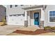 Front entry with teal door, stone accents, and a two-car garage at 34 Windflower Ct, Clayton, NC 27520