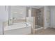 Main bathroom with soaking tub, glass shower, tiled walls and floors, plus a large window at 200 Callandale Ln, Durham, NC 27703