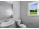 Small half bathroom with white pedestal sink and toilet, and a window overlooking the backyard at 93 Macy Cir, Wendell, NC 27591
