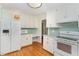 White kitchen features granite countertops, light green tile backsplash, and stainless steel appliances at 11712 Black Horse Run, Raleigh, NC 27613