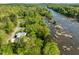 Aerial view of a modern solar paneled home surrounded by lush greenery and a scenic river at 196 Paces Mill Trl, Pittsboro, NC 27312