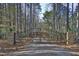 Elegant stone and metal gate with 'Paces Mill' signage, nestled amongst tall pine trees at 196 Paces Mill Trl, Pittsboro, NC 27312