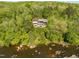 Aerial view of a modern home with a pool surrounded by lush forest and bordered by the river at 196 Paces Mill Trl, Pittsboro, NC 27312