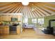 Open-concept yurt interior with kitchenette, wood stove, skylight, and natural light throughout the space at 196 Paces Mill Trl, Pittsboro, NC 27312