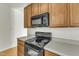 Black stove and microwave in kitchen with wood cabinets at 215 W Chestnut Ave, Wake Forest, NC 27587