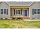 Inviting front porch with wooden pillars, a blue front door, and lovely landscaping at 2857 Greenbrook Dr, Wendell, NC 27591