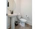 This powder room features a pedestal sink, modern fixtures, and wood-look flooring at 404 Andrews Rd, Durham, NC 27705