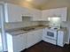 Bright kitchen features white cabinets, dark floors, and modern appliances at 5016 Parkerwood Dr, Knightdale, NC 27545