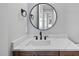 Stylish bathroom featuring a round mirror and modern fixtures atop a dark wood cabinet at 5820 Shawood Dr, Raleigh, NC 27609