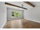 Bedroom with large window overlooking greenery and hardwood flooring with ceiling beams at 5820 Shawood Dr, Raleigh, NC 27609