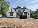 A new two-story home with white painted brick and dark framed windows sits on a sunny lot at 5820 Shawood Dr, Raleigh, NC 27609