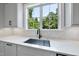 Modern kitchen with light countertops, a deep sink, dark fixtures, and a window overlooking greenery at 5820 Shawood Dr, Raleigh, NC 27609