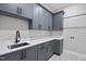 Well-equipped laundry room with gray cabinets, white countertops, and patterned tile flooring at 5820 Shawood Dr, Raleigh, NC 27609