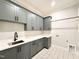 Laundry room boasts grey cabinetry, white countertops, tiled floors, and a sink at 5820 Shawood Dr, Raleigh, NC 27609
