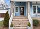 Inviting front porch featuring brick steps, wood door, blue siding, and white railings offers a warm welcome at 1000 Norris St, Raleigh, NC 27604