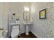 Charming powder room with pedestal sink, decorative mirror, and colorful wallpaper at 1000 Norris St, Raleigh, NC 27604