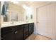 Well-lit bathroom with a double vanity, black cabinetry, white door, and neutral colored tile at 125 Canary Ct. Ct, Raleigh, NC 27610