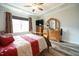 Bright main bedroom with wood floors, ceiling fan, a large window, and dresser with a mounted TV at 125 Canary Ct. Ct, Raleigh, NC 27610