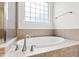 A luxurious bathtub with tile surround and a window for natural light at 1400 Basley St, Wake Forest, NC 27587
