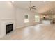 Bright living room featuring light wood floors, a ceiling fan, a fireplace, and views of the kitchen at 1701 Drayton Hall Ln, Sanford, NC 27330