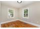 Bright bedroom with hardwood floors and two windows at 1712 Rosetta Dr, Durham, NC 27701