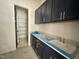 Laundry room with navy blue cabinets, light countertops, tile floors, and a spacious pantry at 1725 Burnette Garden Path, Raleigh, NC 27612