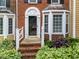 Charming brick townhome featuring a decorative front door, copper bay window, and beautiful landscaping at 4541 Hershey Ct, Raleigh, NC 27613