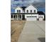 Two-story white home featuring a covered porch, three-car garage, and concrete driveway at 53 Priming Way, Angier, NC 27501