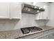 Close up of gas cooktop with stainless steel vent hood at 10310 Sablewood Dr # 108, Raleigh, NC 27617