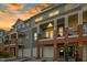 Beautiful townhome exterior showcasing brick accents, covered balconies and garage at sunset at 219 Broadgait Brae Rd, Cary, NC 27519