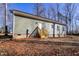 Exterior view of the home showcasing muted green siding, small access stairs, and a natural, wooded backyard setting at 512-A E Graham St, Mebane, NC 27302