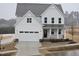 Two-story white farmhouse with a black front door and attached two-car garage at 1013 Prominence Dr., Homesite 22, Durham, NC 27712