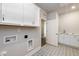 Functional laundry room with white cabinets, a utility sink, and stylish patterned tile floor at 134 Oban Dr, Homesite 133, Sanford, NC 27330
