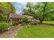 Lush front yard with manicured garden beds, mature trees, and covered parking area at 1741 W Blackman Rd, Dunn, NC 28334