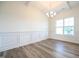 Dining room with white wainscoting, wood floors, modern chandelier, and natural light at 223 Johnson Ridge Way, Four Oaks, NC 27524
