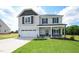 Charming two-story home with a manicured lawn, two-car garage, and inviting front porch at 223 Johnson Ridge Way, Four Oaks, NC 27524